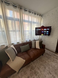 Sink into your plush sectional sofa and enjoy entertainment on the smart TV while natural light filters through elegant curtains in this cozy living space.