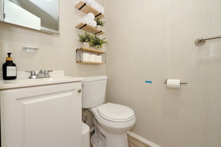 Your private bathroom features modern fixtures, stylish floating shelves, and thoughtful touches like fresh towels and greenery.