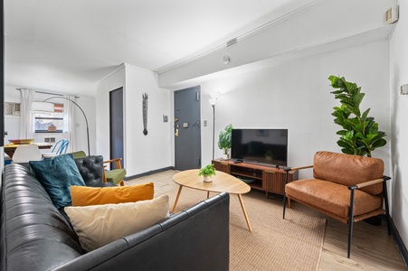 Relax in your stylish living room with modern leather seating, vibrant pillows, and contemporary entertainment center—your perfect retreat.