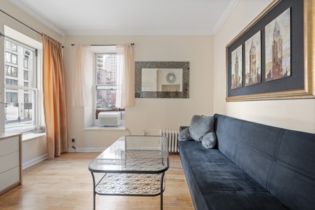 Relax on your plush sofa while gazing at city views through bright windows in this elegant living space.