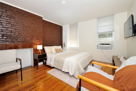Unwind in your serene bedroom featuring exposed brick walls, gleaming hardwood floors, and crisp linens that invite restful nights.