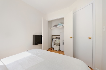 Your cozy bedroom features a comfortable bed, wall-mounted TV for entertainment, and ample closet storage for all your belongings during your stay.