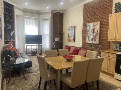 Unwind in your stylish open-plan living space featuring exposed brick walls, modern furnishings, and a fully equipped kitchen.