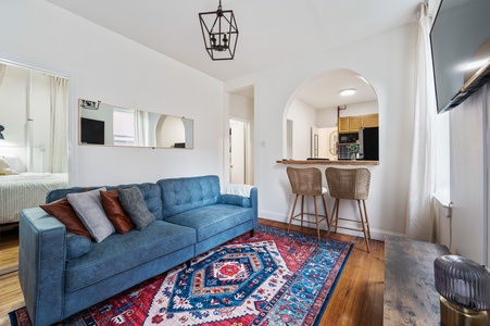 Relax on your plush blue sofa while admiring the vibrant Persian rug beneath your feet in this bright, open-concept living space.