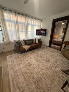 Unwind on your plush leather sofa while streaming your favorite shows on the smart TV in this stylish living space with elegant exposed brick.