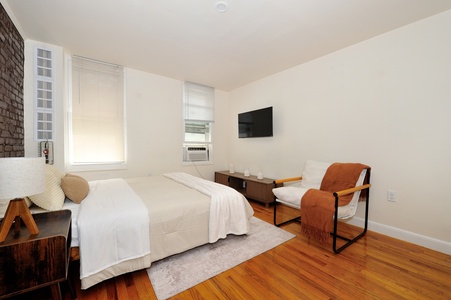 Settle into your serene bedroom with crisp linens, warm wood floors, and modern comforts like AC and TV for a restful stay.