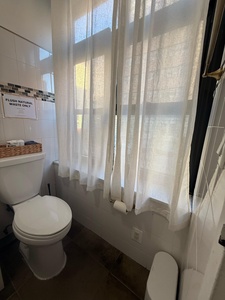 Step into your bright, spotless bathroom where natural light filters through soft curtains, creating a peaceful start to your mornings.