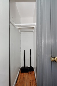 Step into your private walk-in closet with rich hardwood floors and built-in shelving for organized storage.