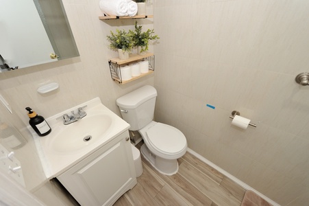 Your private bathroom features clean modern fixtures, floating shelves with fresh greenery, and thoughtful touches for a refreshing start to your day.