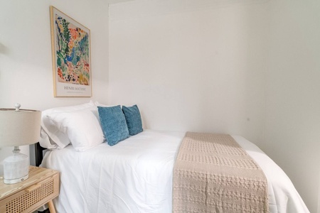 Sink into crisp white linens and plump teal pillows in your serene bedroom, where artistic touches create a peaceful retreat for restful nights.