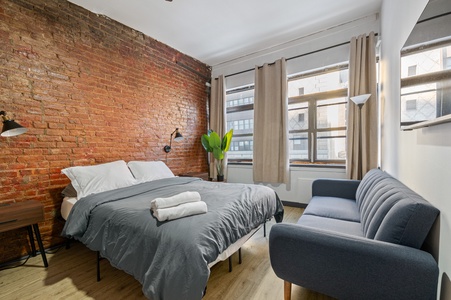 Step into your stylish urban retreat where exposed brick walls meet modern comfort. Sink into the plush armchair after exploring the city.