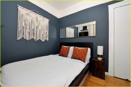 Drift off in your stylish bedroom featuring rich navy walls, crisp linens, and charming bohemian touches that create the perfect cozy retreat.