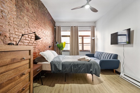 Unwind in your stylish bedroom featuring exposed brick walls, comfortable seating, and modern amenities for the perfect urban retreat.