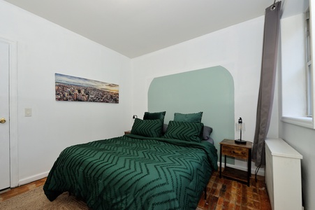 Unwind in your peaceful retreat featuring rich emerald bedding, warm wood floors, and a striking mint accent wall that creates your perfect sanctuary.