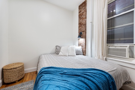 Relax in your cozy bedroom featuring an exposed brick accent wall and modern touches that create the perfect urban retreat.
