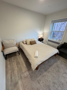 Unwind in your serene bedroom with peaceful forest views and modern comfort, complete with cozy seating for relaxed moments.