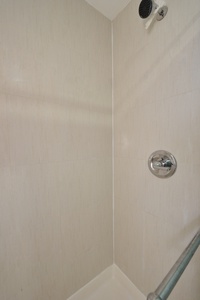 Step into your private shower with modern rainfall showerhead and sleek chrome fixtures for a refreshing start to your day.