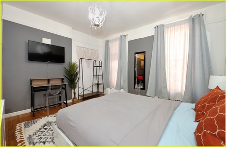 Unwind in your elegant bedroom featuring a crystal chandelier, flat-screen TV, and stylish workspace—your perfect retreat.