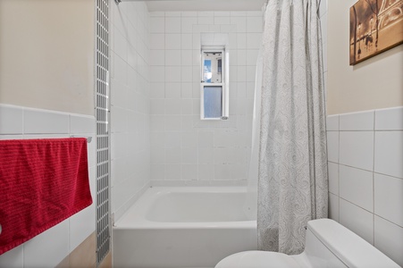 Refresh in your private bathroom featuring a full tub-shower combo with fresh towels and natural light from the window.