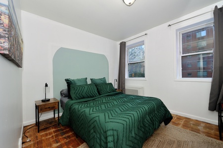 Relax in your stylish bedroom with striking emerald bedding and warm hardwood floors beneath your feet.