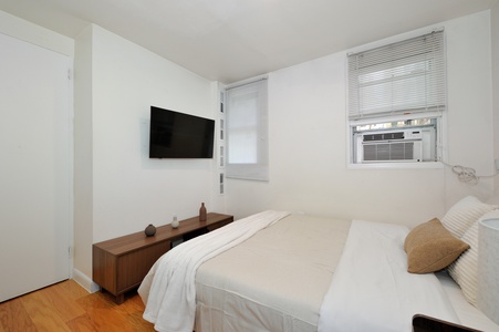 Unwind in your serene bedroom with crisp white linens, a wall-mounted TV for evening relaxation, and air conditioning for perfect comfort.