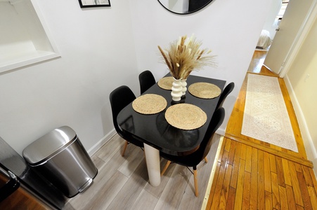 Your stylish dining table awaits intimate meals, perfectly set with warm placemats and elegant touches in this bright, welcoming space.