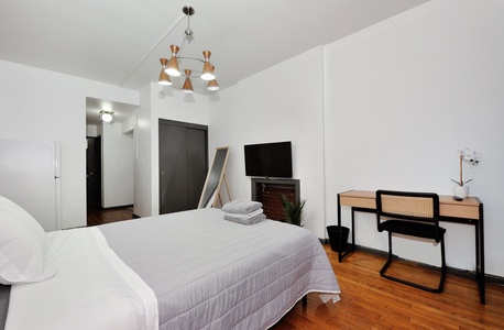 Your stylish bedroom features modern furnishings, crisp linens, and thoughtful touches like the elegant chandelier that creates a warm, welcoming atmosphere for restful nights.