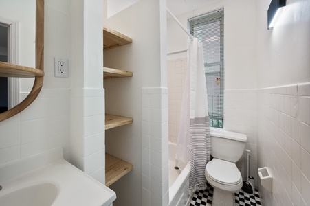 Step into your bright, modern bathroom featuring thoughtful details like built-in wooden shelving for your essentials and a window that fills the space with natural light.