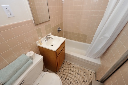 Your private bathroom features classic tile work, a full tub with shower, and thoughtful touches like fresh towels waiting for your arrival.