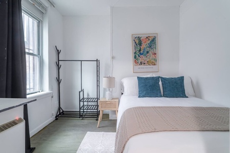 Rest peacefully in your bright bedroom where vibrant teal pillows complement the botanical artwork, creating a serene modern sanctuary.