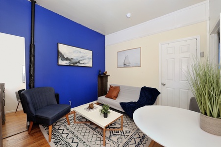 Unwind in your stylish living space with vibrant blue accent wall, plush seating, and coastal artwork creating a perfect retreat.