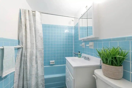 Refresh in your bright blue-tiled bathroom with a relaxing tub, modern sink, and thoughtful plant touches.