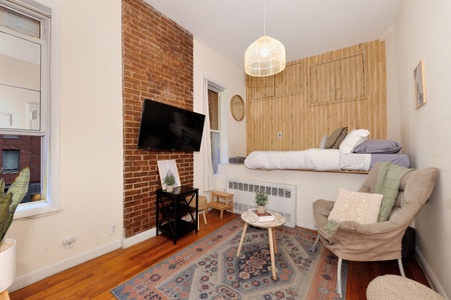 Your cozy studio blends exposed brick charm with modern comfort, featuring a comfortable bed and relaxing seating area.