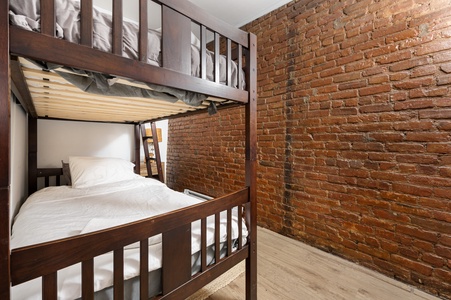 Sleep soundly in your cozy bunk bed surrounded by charming exposed brick walls that add warmth and character to your urban retreat.
