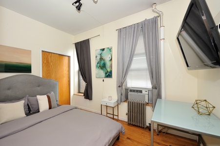 Your stylish bedroom awaits with plush bedding, modern artwork, and a dedicated workspace for perfect comfort.