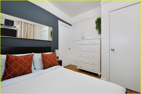 Sink into crisp white linens with vibrant accent pillows in your thoughtfully designed bedroom, complete with ample storage and charming decor touches.