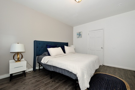 Your peaceful bedroom features a plush navy headboard and crisp white linens, creating the perfect sanctuary for restful nights.