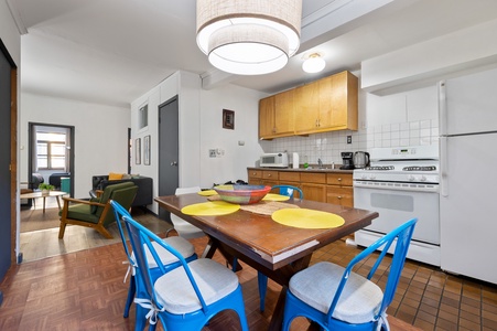 Your open-concept kitchen and dining area features modern appliances, warm wood cabinets, and cheerful blue chairs for memorable meals together.