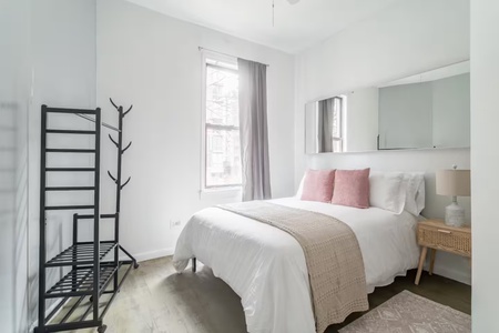 Your peaceful bedroom sanctuary features crisp white linens with soft pink accents and natural light streaming through windows.