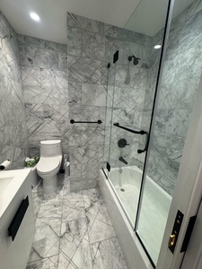 Step into your luxurious marble bathroom featuring a deep soaking tub and spacious glass-enclosed shower with modern fixtures.