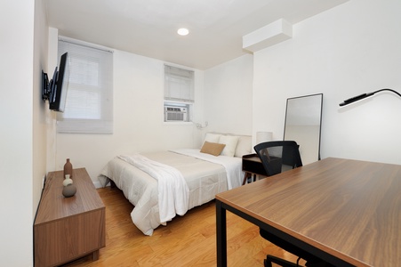 Your bright bedroom offers crisp white linens, a dedicated workspace, and modern amenities for a restful stay.