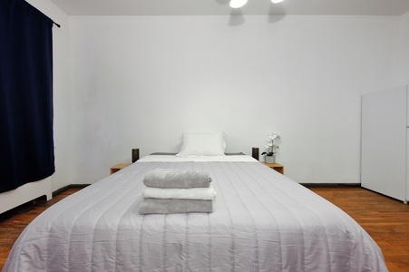 Sink into crisp white linens in your serene bedroom, where warm wood floors and minimalist design create the perfect retreat for restful nights.