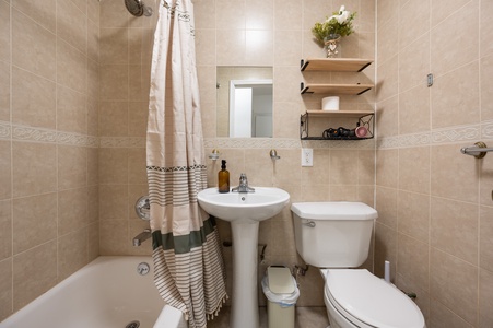Refresh in your own private bathroom with warm beige tiles, a relaxing tub-shower combo, and thoughtful touches like floating shelves for your essentials.