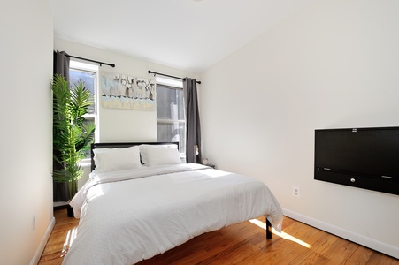 Sink into crisp white linens in your serene bedroom, where warm hardwood floors and natural light create the perfect retreat for restful nights.