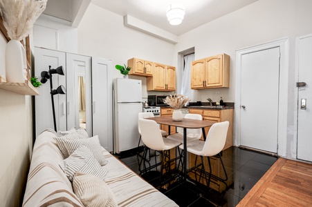 Your stylish studio features a full kitchen with modern appliances, cozy seating, and warm wood accents for comfortable city living.