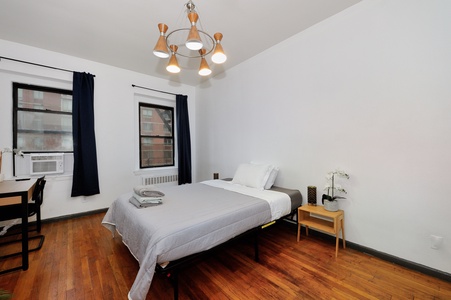 Rest peacefully in your bright bedroom with city views, warm wood floors, and stylish mid-century lighting creating the perfect urban retreat.