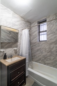 Step into your sleek marble bathroom featuring a full tub-shower combo with fresh linens and modern vanity for your comfort.