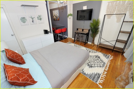 Your stylish bedroom combines modern comfort with artistic touches, featuring warm wood floors and thoughtful design elements for your perfect stay.