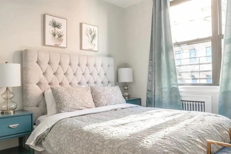 Drift off in this serene bedroom featuring a plush tufted headboard, soft linens, and gentle natural light streaming through your window.