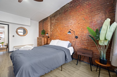Unwind in your stylish bedroom with exposed brick walls, crisp linens, and modern touches creating the perfect urban retreat.